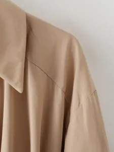 Primo piano sul colletto a revers elegante e design delle spalle in beige classico.