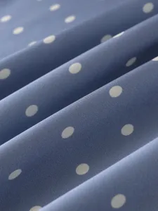 Blue satin fabric detail with white polka dots, smooth texture and elegant drapes.