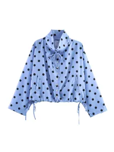 Blusa a maniche lunghe blu con pois neri, elegante collo con coulisse e chiusura con bottoni.