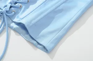 Detailopname van het lichtblauwe satijnen corset met vetersluiting en nette stiksels.