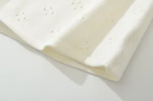 Detailed view of the breathable hollow-out knit fabric in cream white, smooth and delicate.