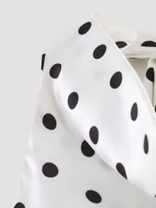 Detalle de tela de satén blanco con lunares negros clásicos para ropa de verano.