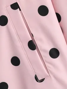 Dettaglio in primo piano di una camicia rosa a maniche lunghe con pois neri classici.