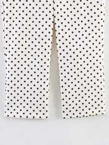 Black and white polka dot trousers detail view, classic stylish women's clothing piece.