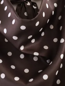 Primer plano del top halter de satén marrón oscuro con elegantes lunares blancos y cuello drapeado.