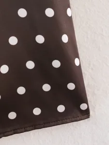 Primer plano de tela de lunares marrón y blanco, mostrando textura y dobladillo limpio.