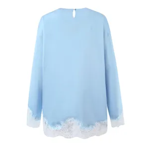 Detail view of light blue long sleeve top featuring delicate white lace trim hem and cuffs.