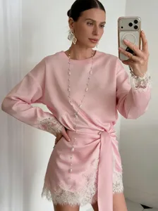 Chic pink satin long sleeve top featuring delicate white lace trim and stylish waist tie detail.