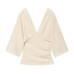 Detailed view of the elegant beige deep V-neck top with wide sleeves and ruched front design.