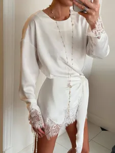 Exquisite white satin long sleeve top featuring delicate lace trim on cuffs and irregular hemline.