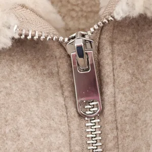 Close-up detail of metallic zipper and soft fleece shearling fabric on the cozy jacket.