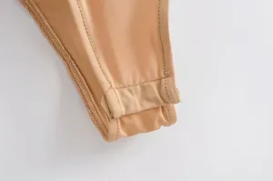 Close-up detail of the nude bodysuit edge showing premium stitching and soft stretch fabric.