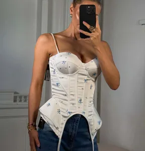 Close-up detail of white floral corset top featuring spaghetti straps and asymmetric hem.