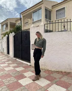 Stylish olive green cropped long-sleeve shirt with practical pocket details worn outdoors.