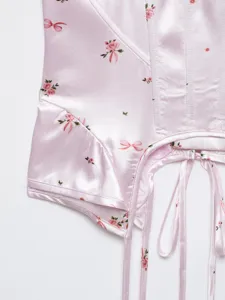 Pink floral corset camisole detail showing satin fabric, rose print and lace-up straps.