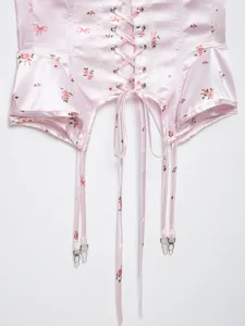 Pink floral satin corset top detail showing front lacing ribbons and metal garter clips.