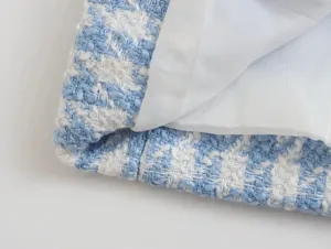 Close-up detail of blue and white houndstooth tweed fabric with smooth white inner lining.