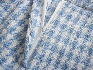 Blue white houndstooth tweed fabric detail close up with white zipper for women clothing.