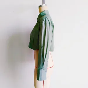 Side detail view of a sage green cropped long-sleeve shirt with front pocket design.