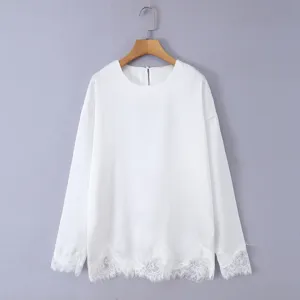 Close-up view of a white long-sleeve blouse featuring elegant lace trim cuffs and hem detail.