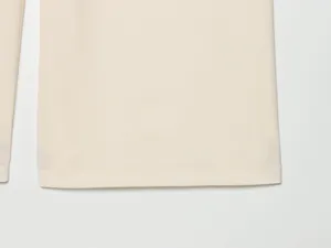Close up view of womens wide leg trousers hem detail showing neat stitching and soft fabric texture.