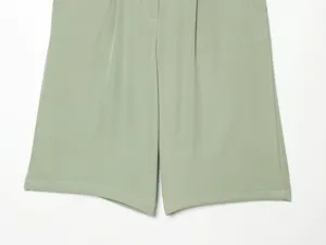 Close-up detail shot of light green women's high-waisted shorts featuring front pleats.