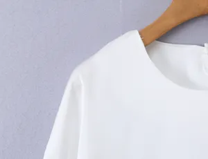 Detailed view of women's solid white round neck blouse, elegant apparel design and fabric.