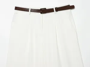 Close-up of high-waisted pleated white shorts featuring a stylish brown textured belt detail.