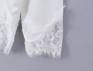 White long sleeve top delicate lace cuff detail, elegant apparel texture close-up view.