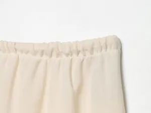 Beige wide-leg pants elastic waistband close-up detail, smooth fabric texture presentation.