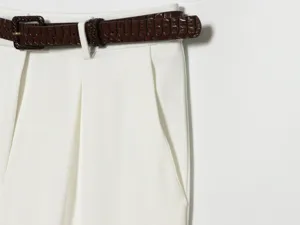 Detail view of women summer high-waisted pleated white shorts featuring a stylish brown belt.