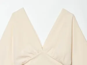 Detail view of beige women's deep V-neck short sleeve top with stylish pleated bust design.