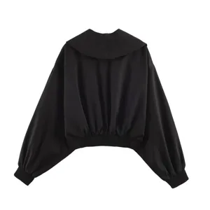 Close-up detail shot of the black cropped jacket featuring a large collar and lantern sleeves.