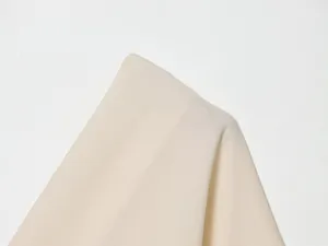Close-up detail view of soft beige knit fabric for women summer top, smooth fine texture.