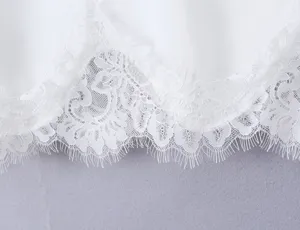 Detailed close-up of white silk fabric with elegant delicate lace trim for women fashion top.