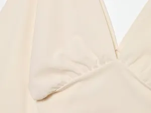 Beige deep V-neck top fabric and gathered detail close-up view, elegant women's apparel.