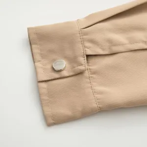 Détail de manche de veste femme kaki, tissu sergé de qualité avec bouton métal, style épuré.