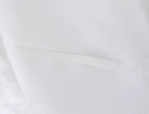 Close-up view of white fabric and stitching detail showcasing fine garment craftsmanship.