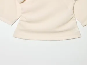 Detail shot of women's short-sleeve top in light beige with ruched side design and soft fabric.