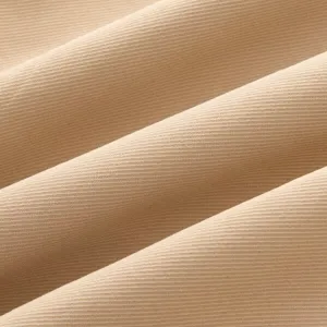 Gros plan sur le tissu d'une veste pour femme beige, avec un tissage sergé et une texture douce.