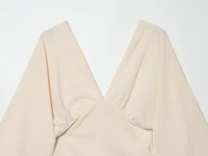 Close up view of the beige deep v-neck short sleeve top showing fabric detail and gathered design.