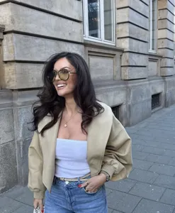 Detail shot of chic beige retro cropped jacket with lapel and lantern sleeves in street scene.
