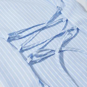 Primo piano sui dettagli della camicia a righe azzurre con graziosi nastri stringati.