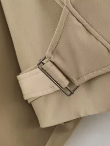 Close-up detail of a classic khaki trench coat featuring a stylish metal buckle and strap.