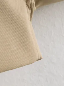 Khaki twill fabric detail closeup of women coat, showing fine texture and neat stitching.