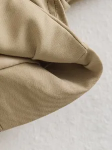 Close-up view of khaki twill fabric texture, showcasing fine stitching and garment details.