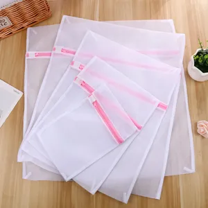 Lot de sacs à linge en maille blanche avec fermetures éclair roses pour vêtements délicats.