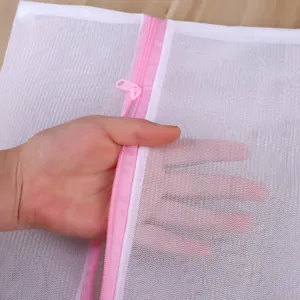 Filet à linge blanc en mesh avec fermeture éclair rose pour protéger les vêtements délicats