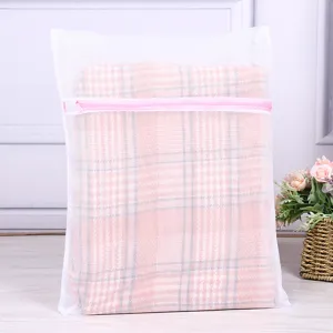 Sac à linge en filet blanc avec fermeture éclair rose pour le lavage des vêtements.
