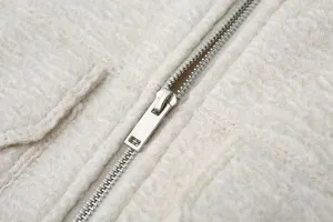 Detailed close-up view of fluffy teddy fleece jacket zipper and soft textured fabric.